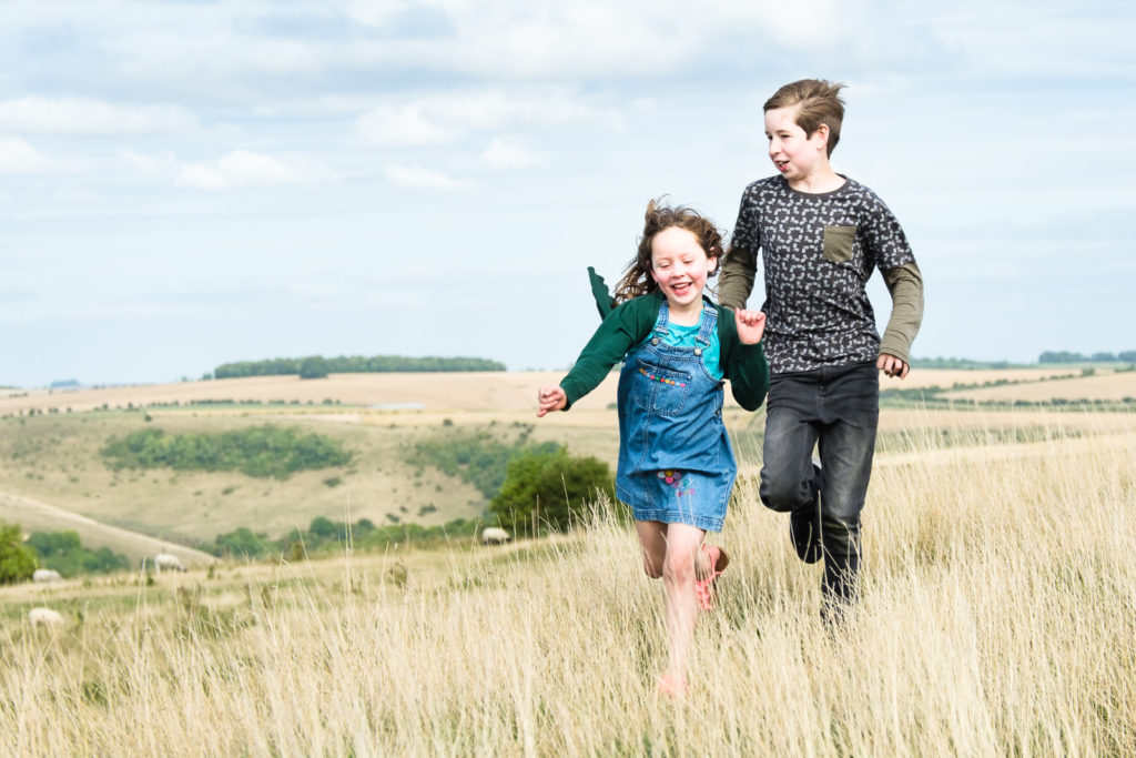 Family photo session in Wiltshire with young brother and sister running outdoors