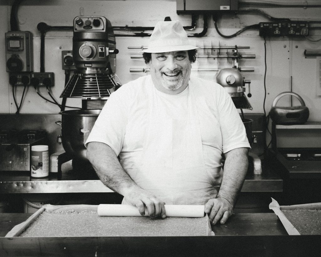 Business storytelling photography of a baker making a tray of flap jacks at Joes Bakery in Bristol, smiling and looking to camera.