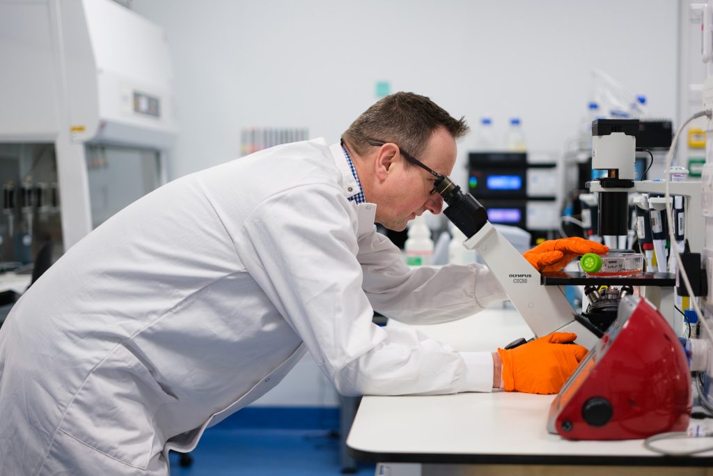 Male R&D chemist viewing samples with a microscope