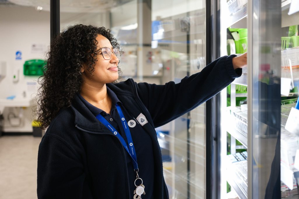 Female worker selecting packaged medication in a large pharmacy production unit