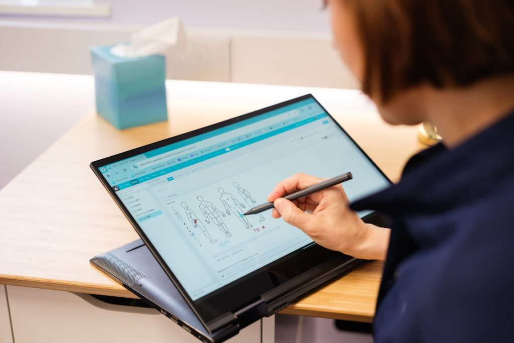 Osteopath recording client notes during a clinical session