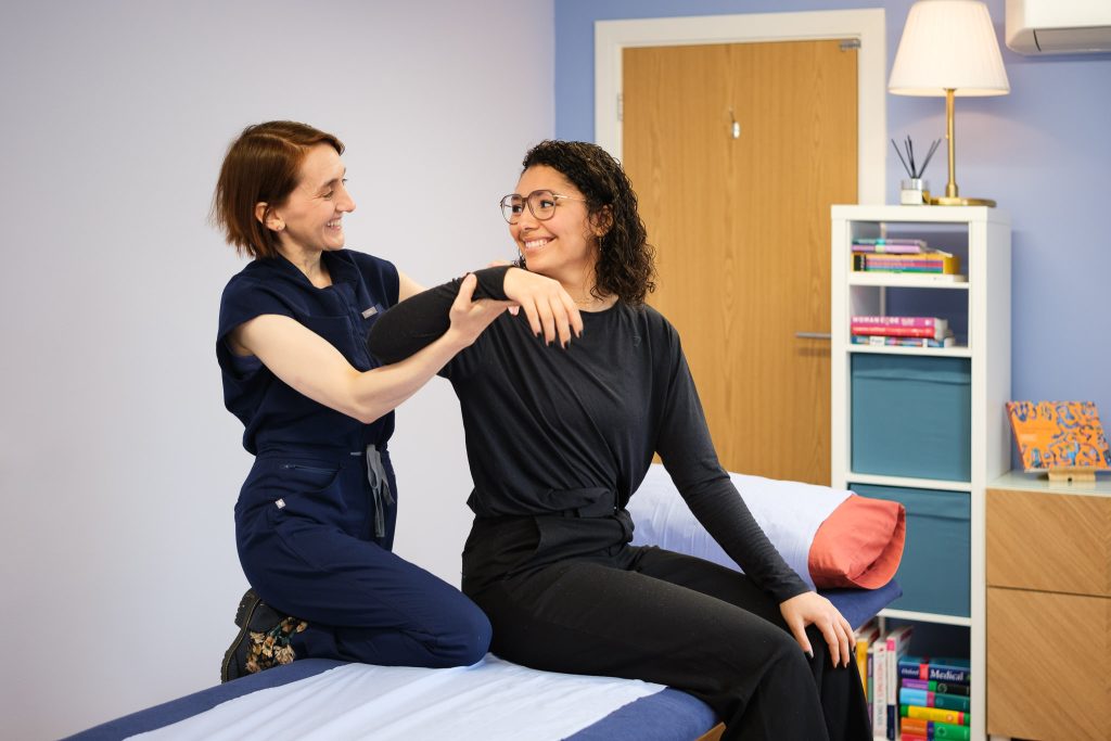Healthcare Photography - Osteopath examining a client's shoulder and arm movement during a clinical session