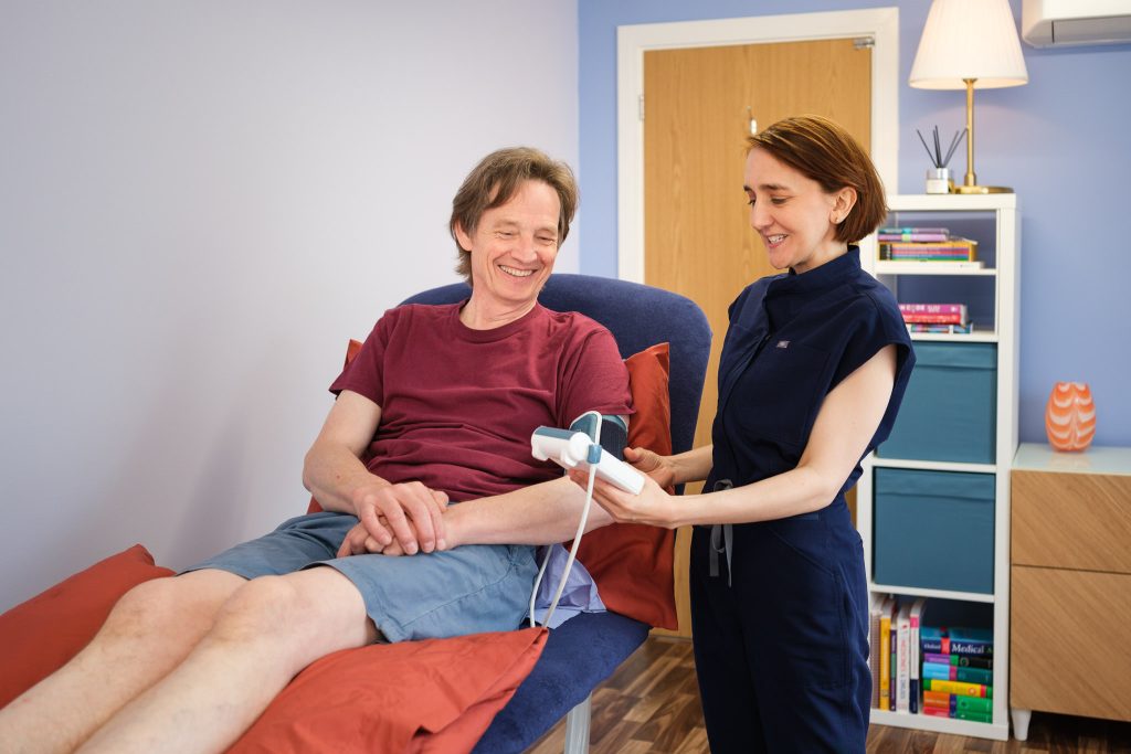 Female osteopath checking a client's blood pressure in clinic