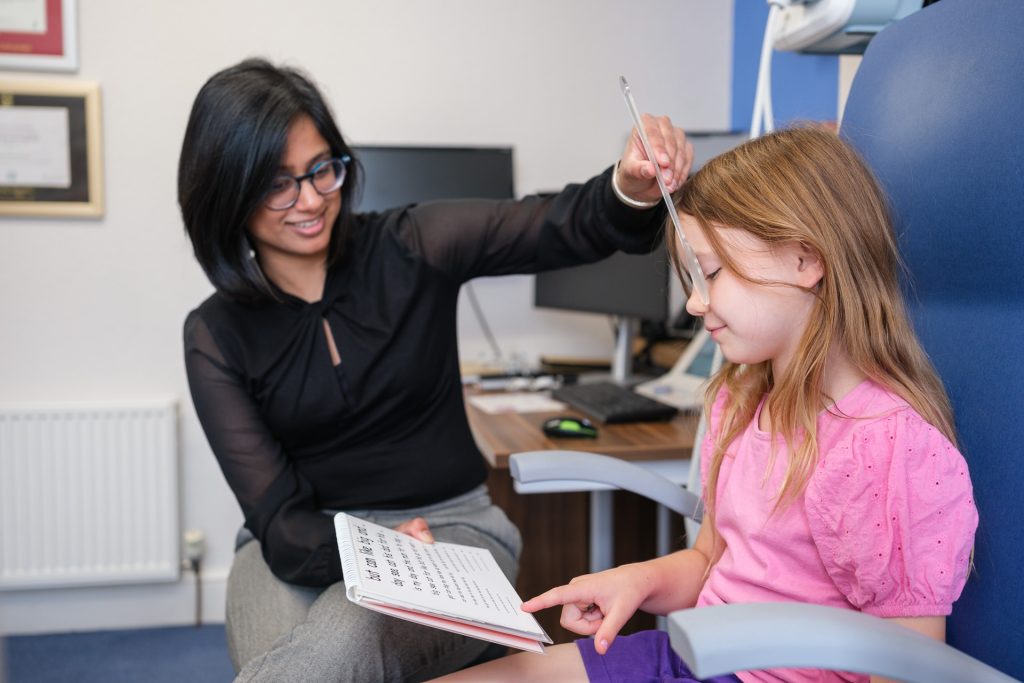 Young girl reading distance eye test with an optician