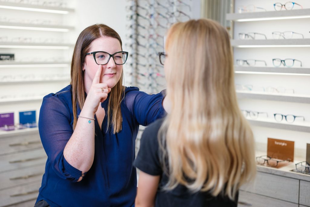 Young girl having glasses fitted by a dispensing optician