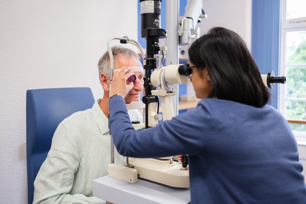 Male patient having an eye test in a brightly lit consulting room