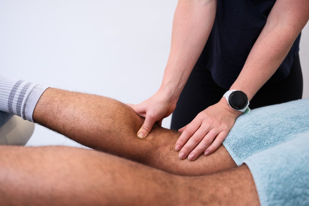 Physiotherapist testing leg muscles with a male client