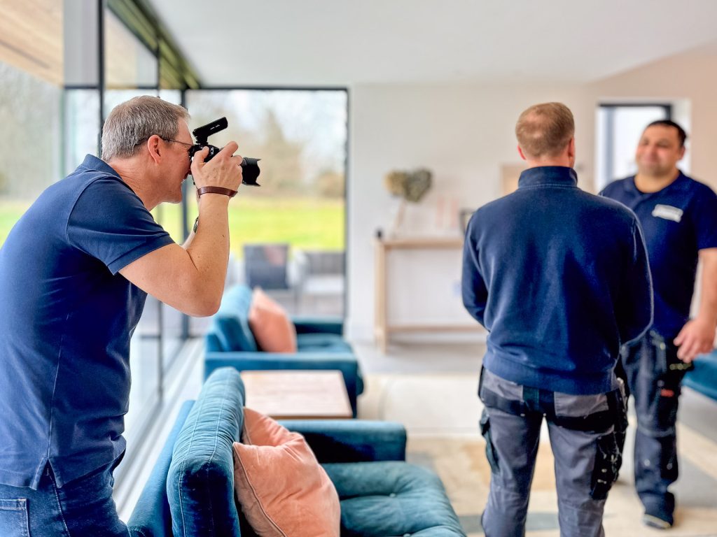 Nick Cole photographing two heating engineers as they discuss a project in a client's home