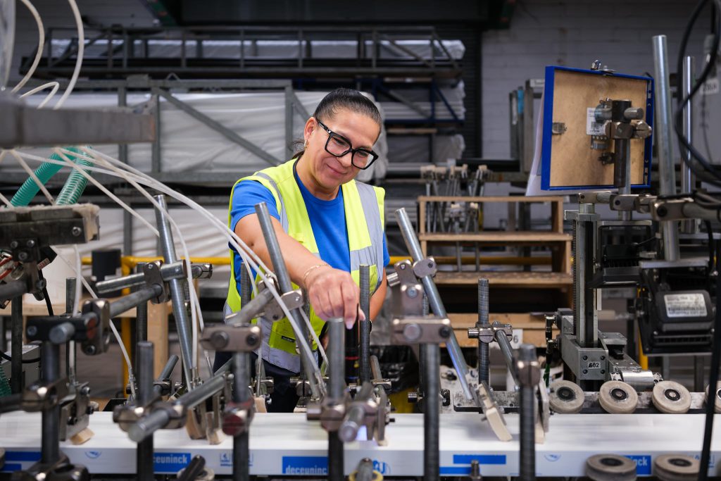 Manufacturing photography showing a female operative checking settings on the production line