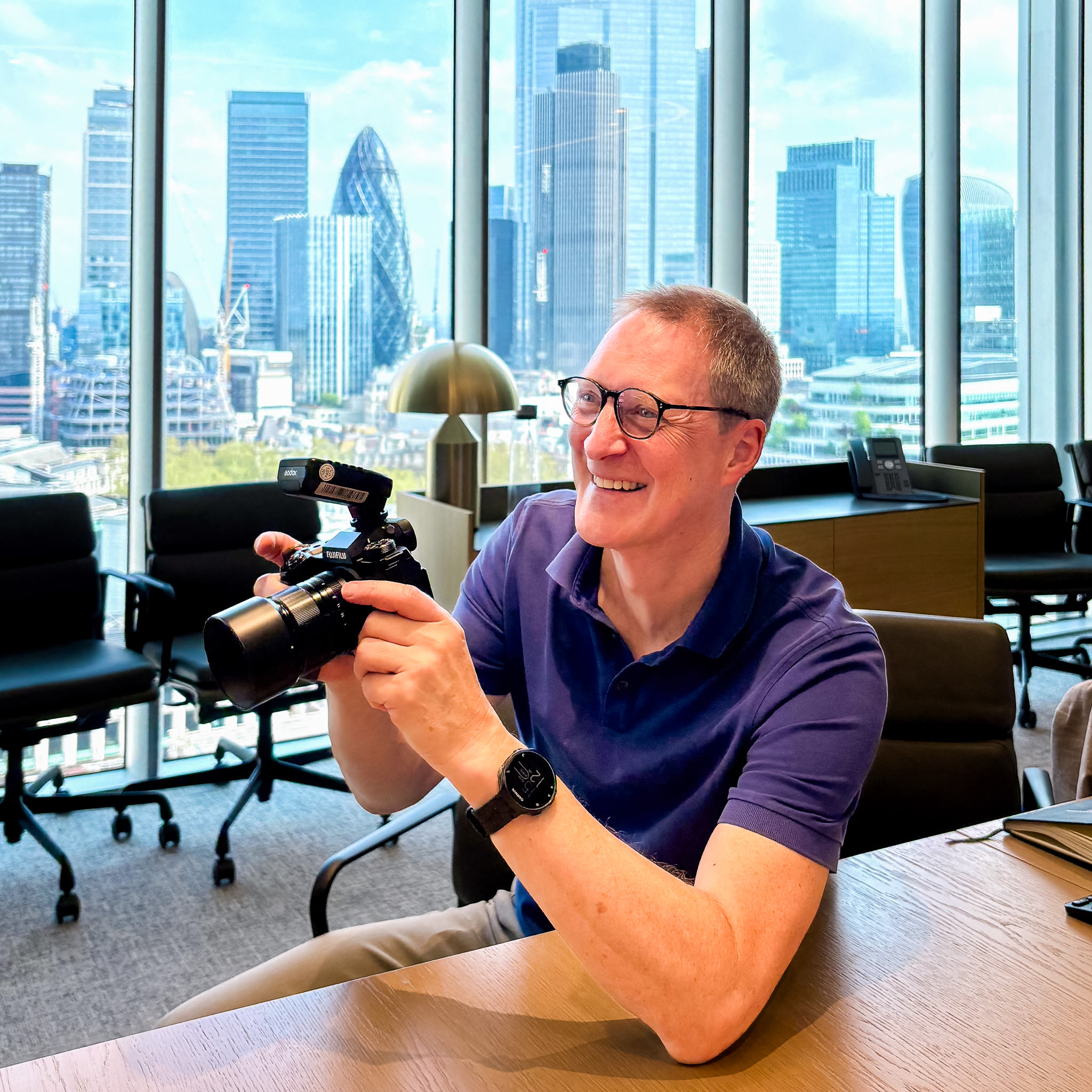 Nick Cole from Nick Cole photography - a behind the scenes photo of Nick holding his camera in a board room location.
