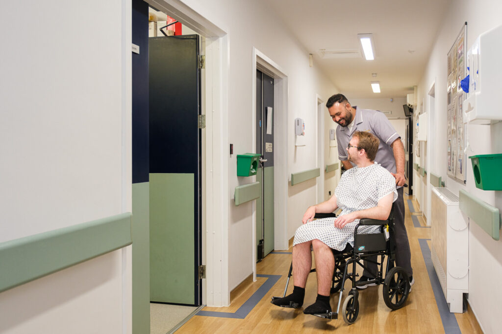 Patient being assisted through a hospital corridor at The New Foscote Hospital