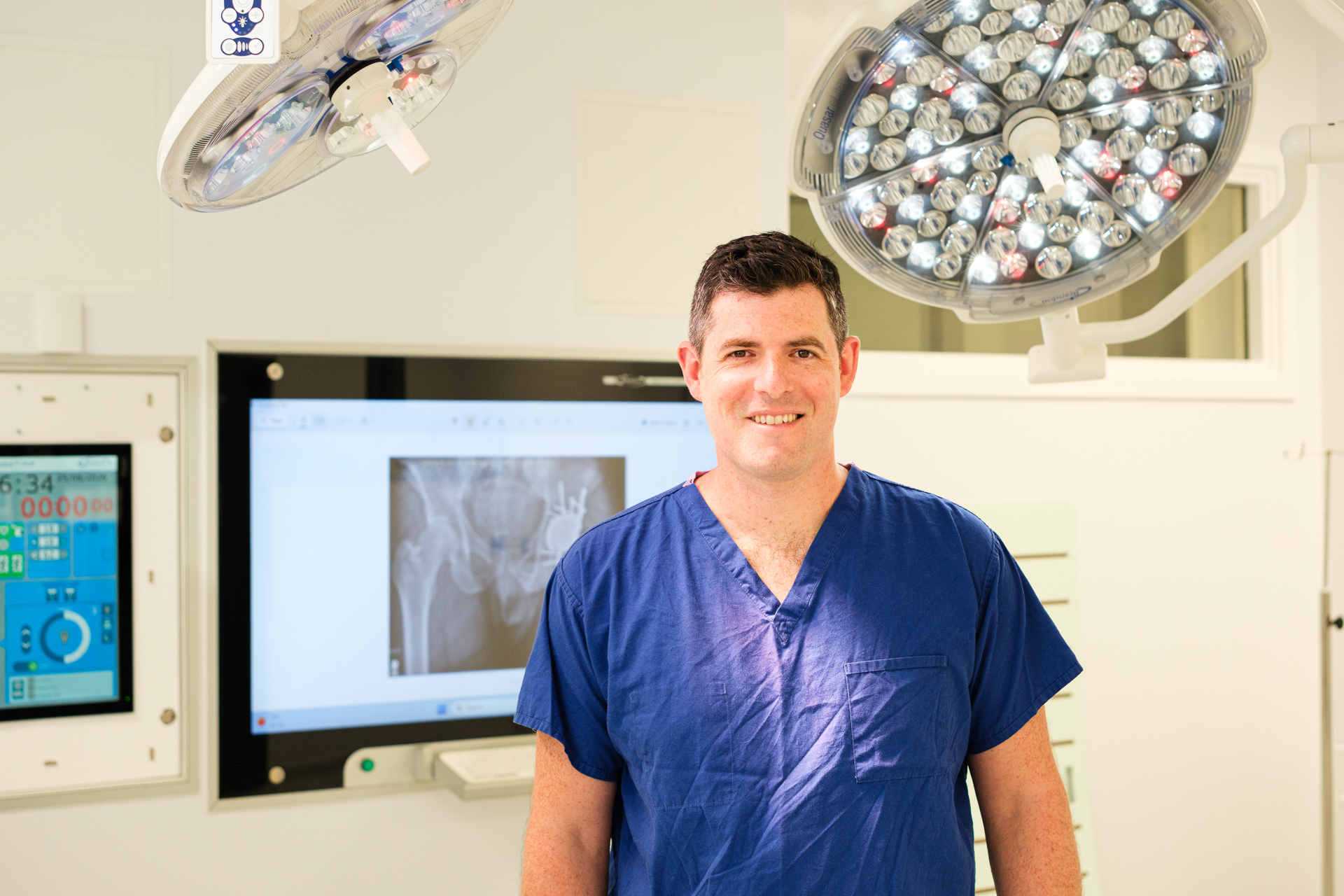 Portrait of consultant orthopaedic surgeon James Berwin in surgical scrubs in an operating theatre.