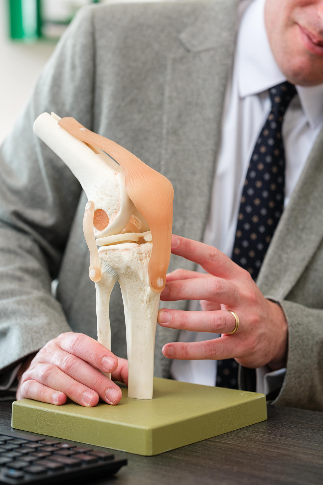 Close-up of James Berwin demonstrating knee anatomy using a joint model.
